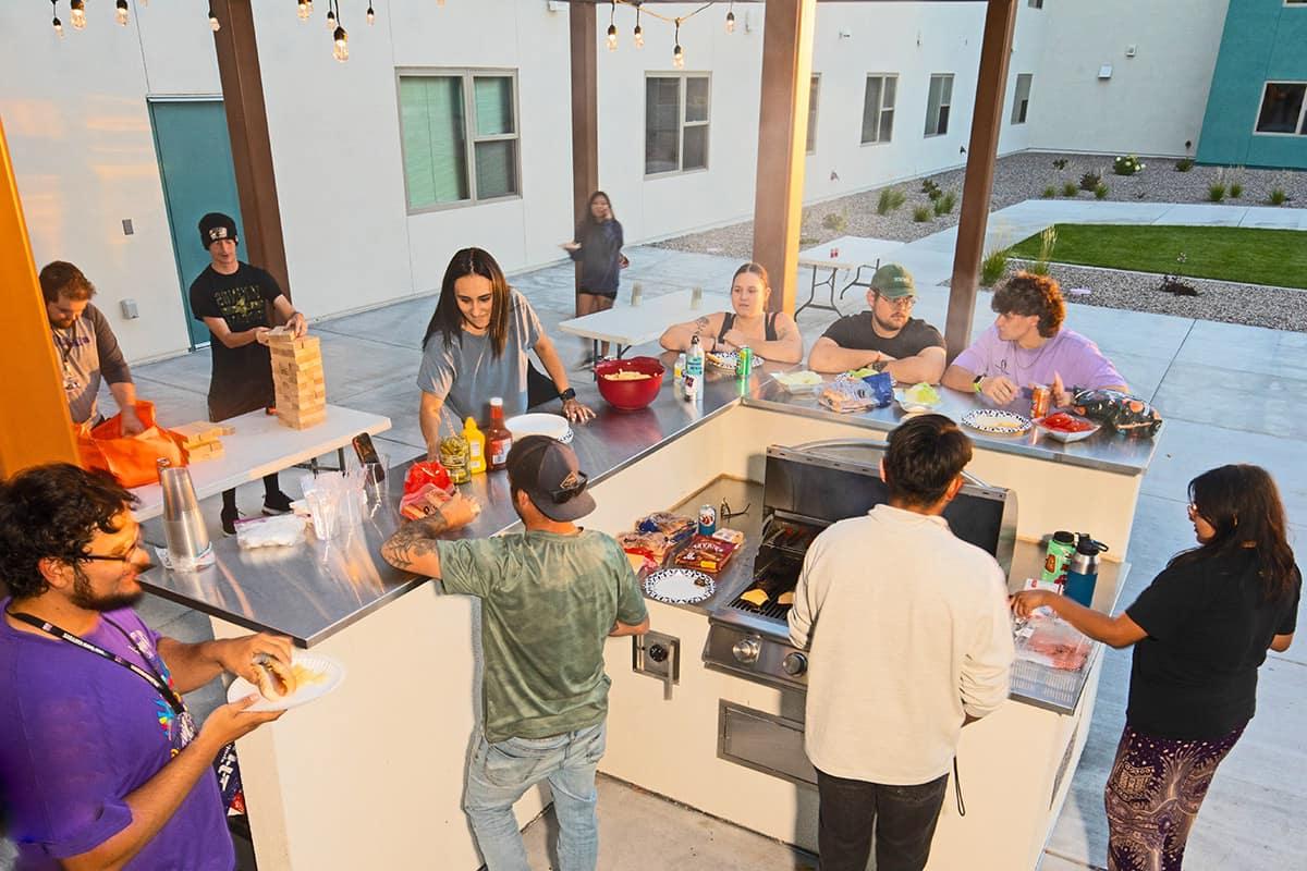 SJC students hang out around the outdoor BBQ grill on the patio at Student Housing enjoying games and food..